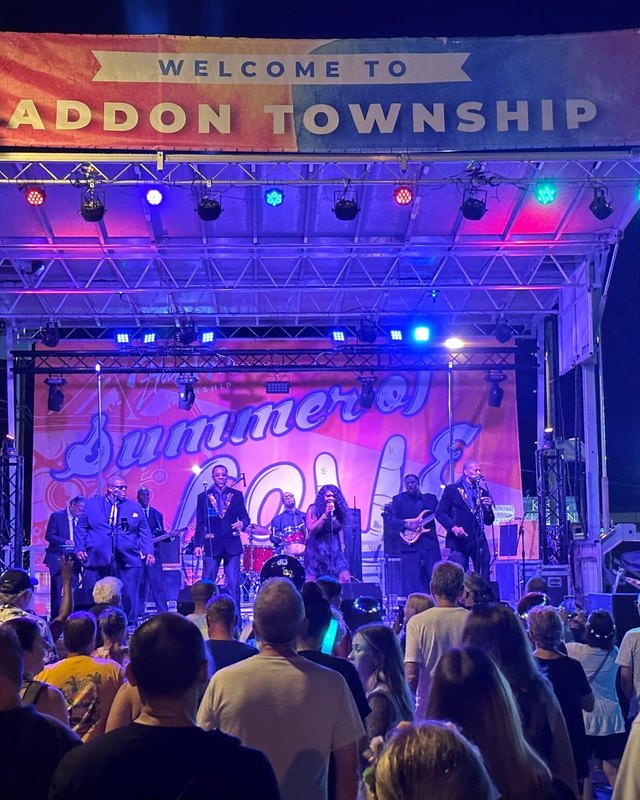 Crowd gathered before a lit stage under a Welcome to Haddon Township banner at night.
