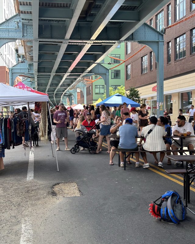 Crowd of shoppers and visitors browsing vendor tables under the elevated train tracks at Under the El Bazaar