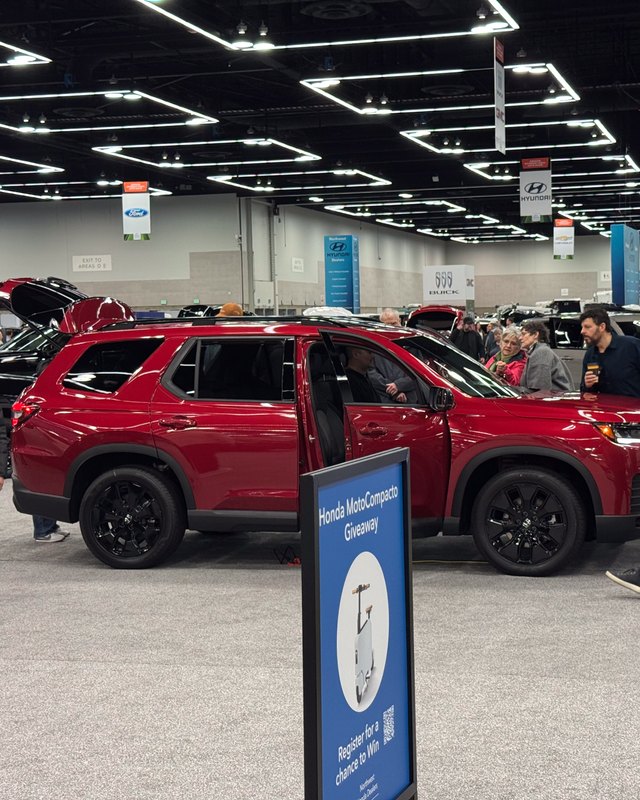 Shoppers gather around a red SUV on display inside the Oregon Convention Center show hall.