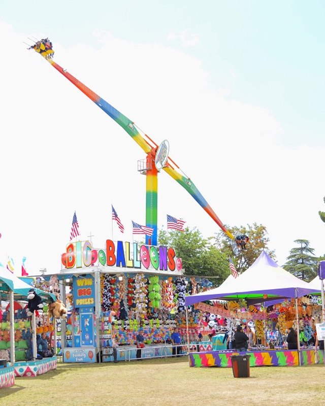 Colorful carnival ride and booth tents at the Maricopa County Fair on a sunny day