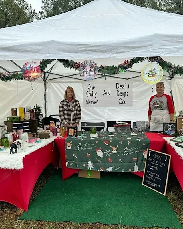 Vendor booth under a white tent with red tablecloths and Christmas ornaments on display.