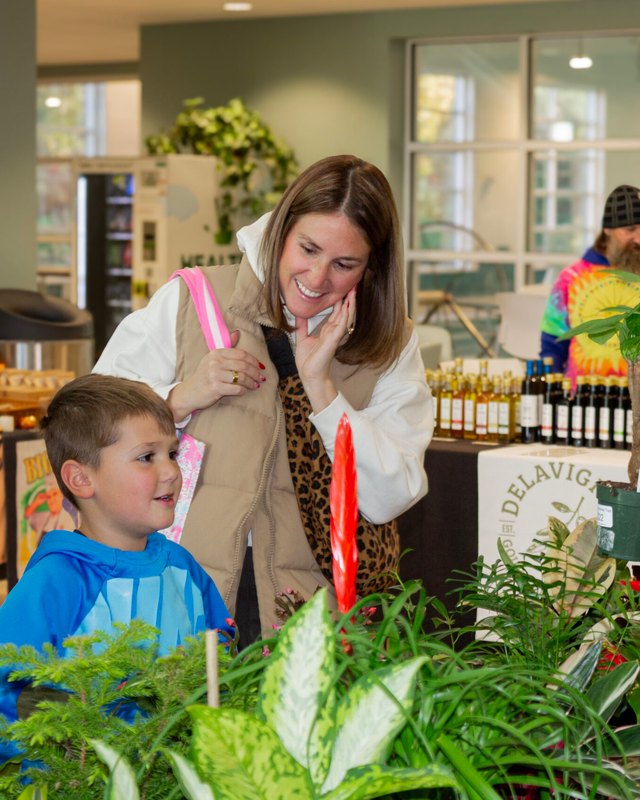 Shoppers and vendors at a product table inside the Newtown Community Center market