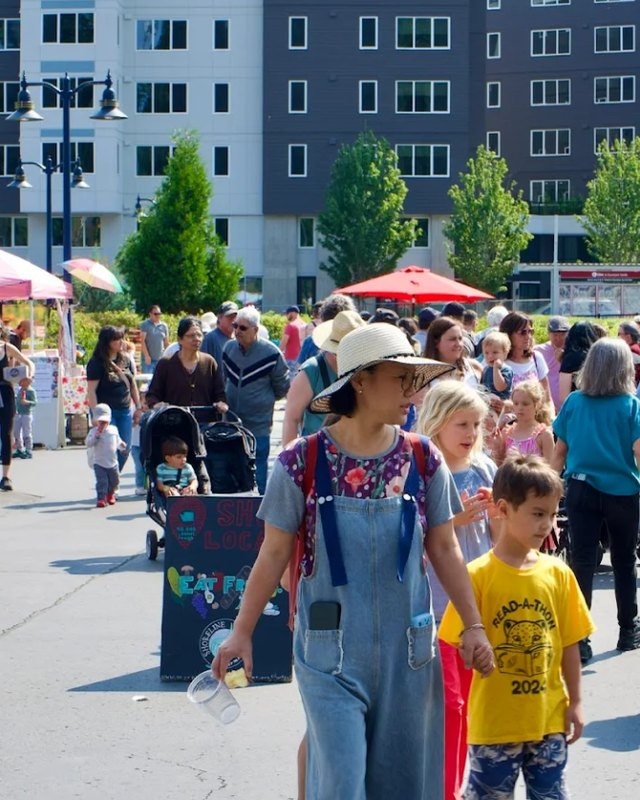 Shoppers and families walking between market tents at the Shoreline Farmers Market.