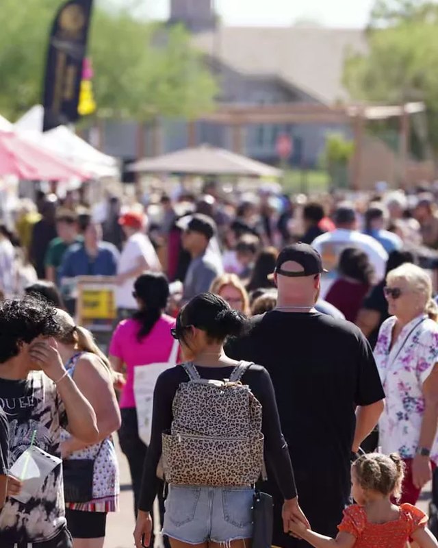 Shoppers and families walking among market tents at the Desert West Market in Avondale.