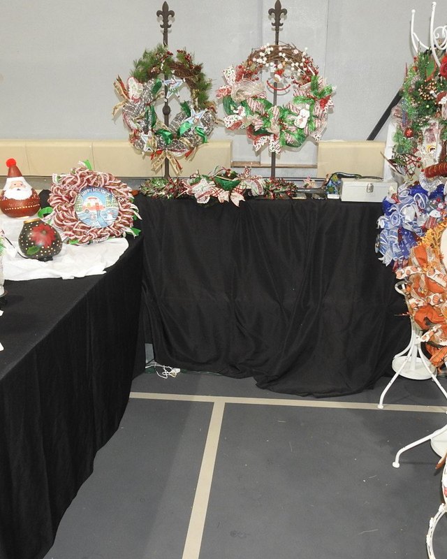 Holiday craft ornaments displayed on black-draped tables inside an indoor event hall.