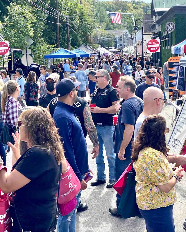 Crowd of visitors walking along a village street past vendor tents at the Georgetown Day street fair.