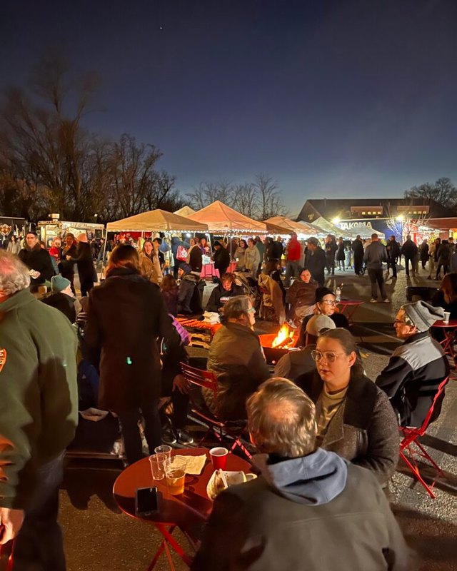 Evening crowd gathered among market tents and fire pits at the Takoma Park holiday market.