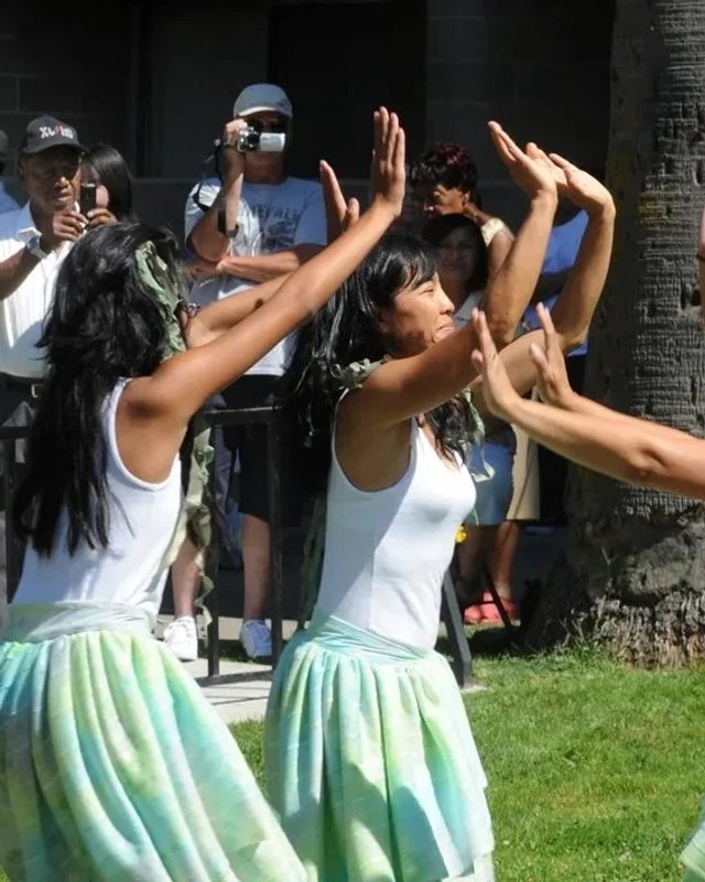 Dancers in white and green skirts performing before a crowd at the Barrio Fiesta Stockton event.