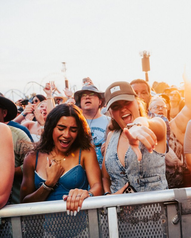 Two women laughing at the barrier in a crowd at a Bourbon & Beyond festival