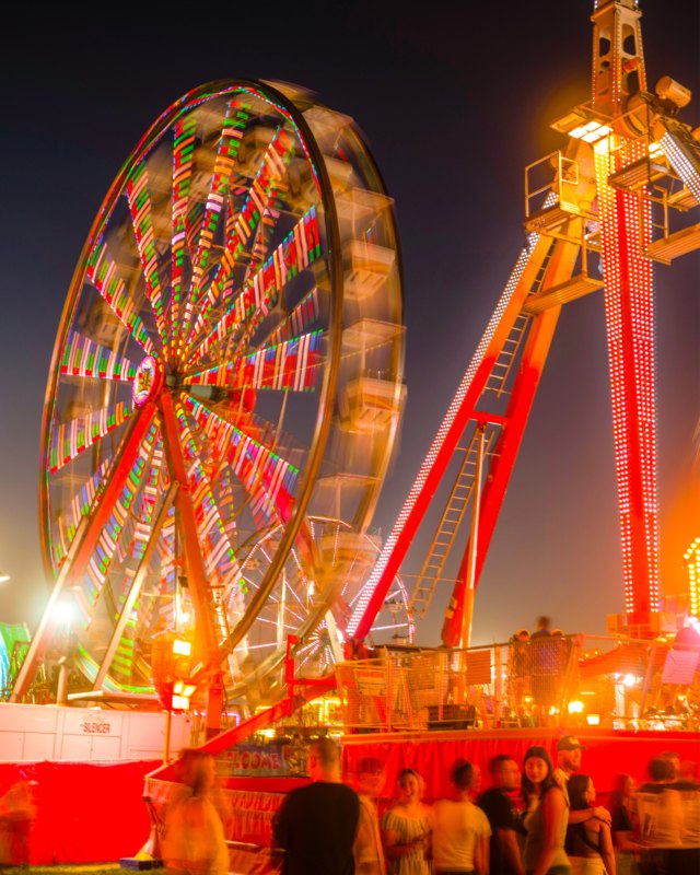 Ferris wheel and thrill ride lit up at night at the Western Idaho Fair