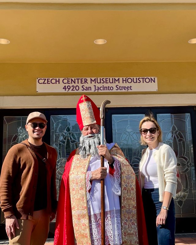 Mikuláš in red robes with two visitors at the entrance of the Czech Center Museum Houston