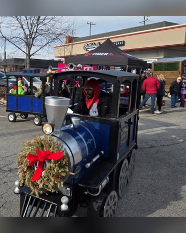 Holly Express train ride cart decorated with a wreath, with people riding it at a winter market.