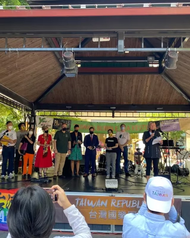 Performers and speakers on a stage under a wooden canopy at the Taiwan Bubble Tea Festival, with a Taiwan Republic banner behind them.