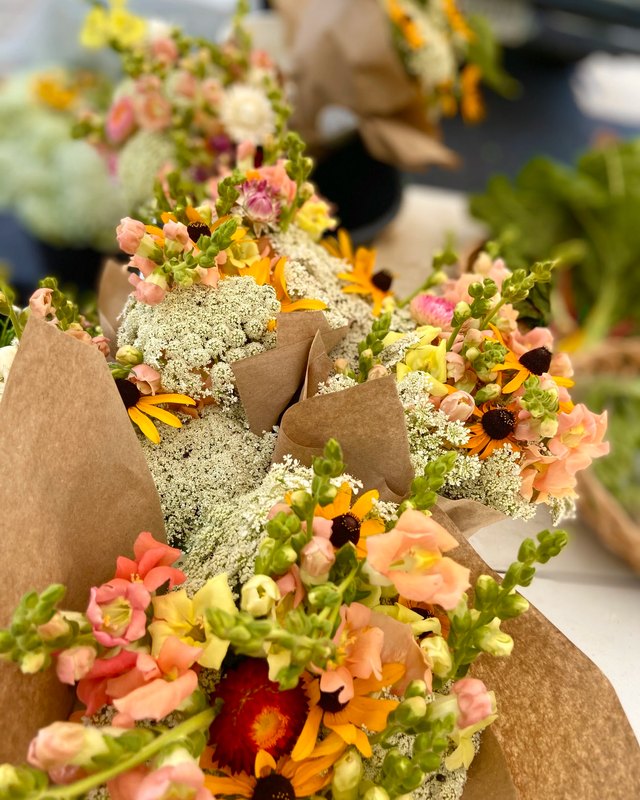Bouquets of mixed flowers wrapped in kraft paper at a market stall.