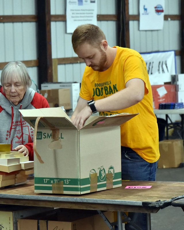 Two volunteers packing books into boxes at a book fair table