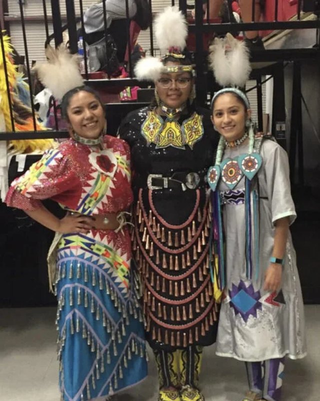 Three Native dancers in colorful regalia stand together for a photo at the Seven Arrows Powwow.