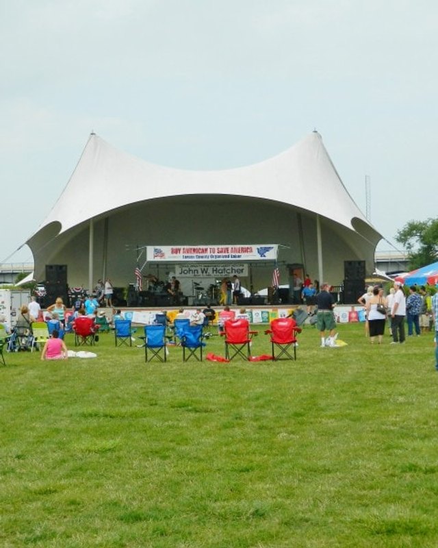 Stage with white tent and people in lawn chairs and tents at the Lorain County Organized Labor Day Festival