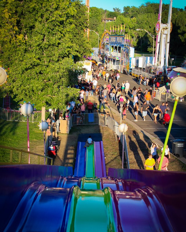 Crowds walking past carnival rides at the Wheat Ridge Carnation Festival midway