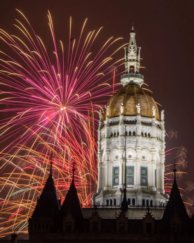 Fireworks bursting over the Connecticut State Capitol dome at night