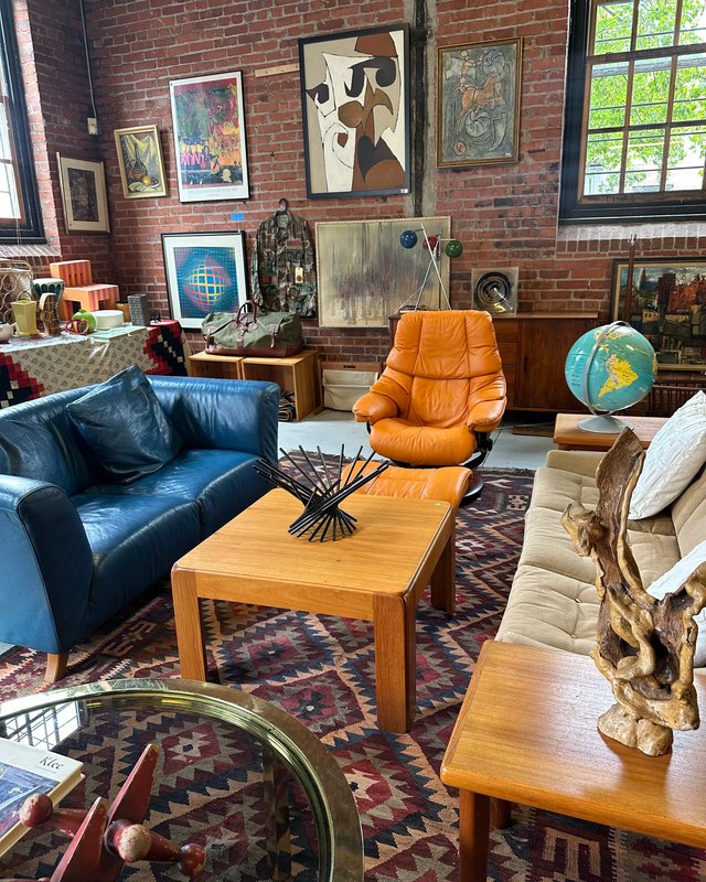 Vintage furniture, framed art and décor arranged in a brick-walled loft space for the Vintage Design Market