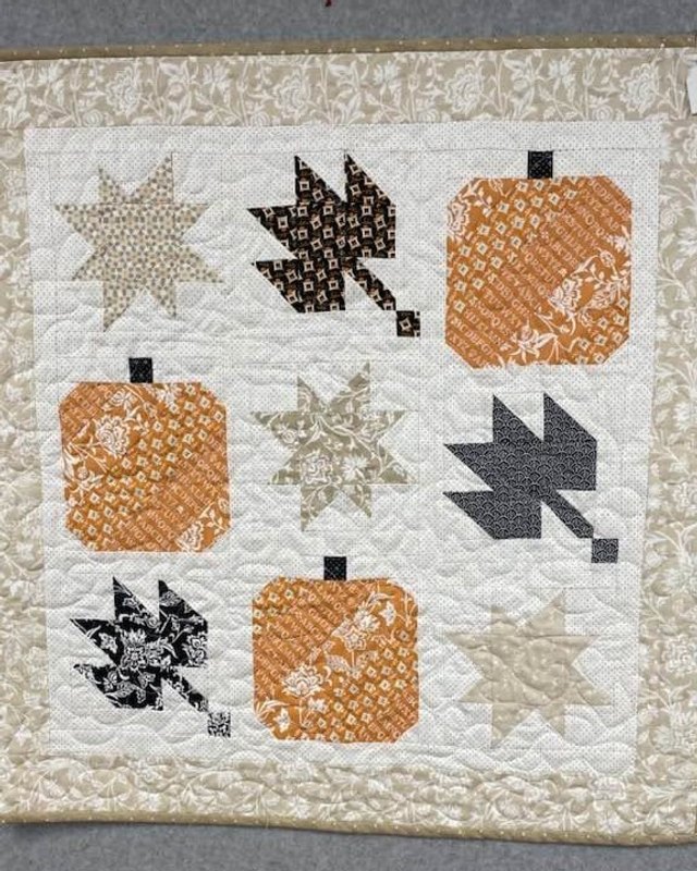 Autumn-themed quilt with pumpkins and leaf blocks, one of the quilts for sale at the Trinity Quilters bazaar.
