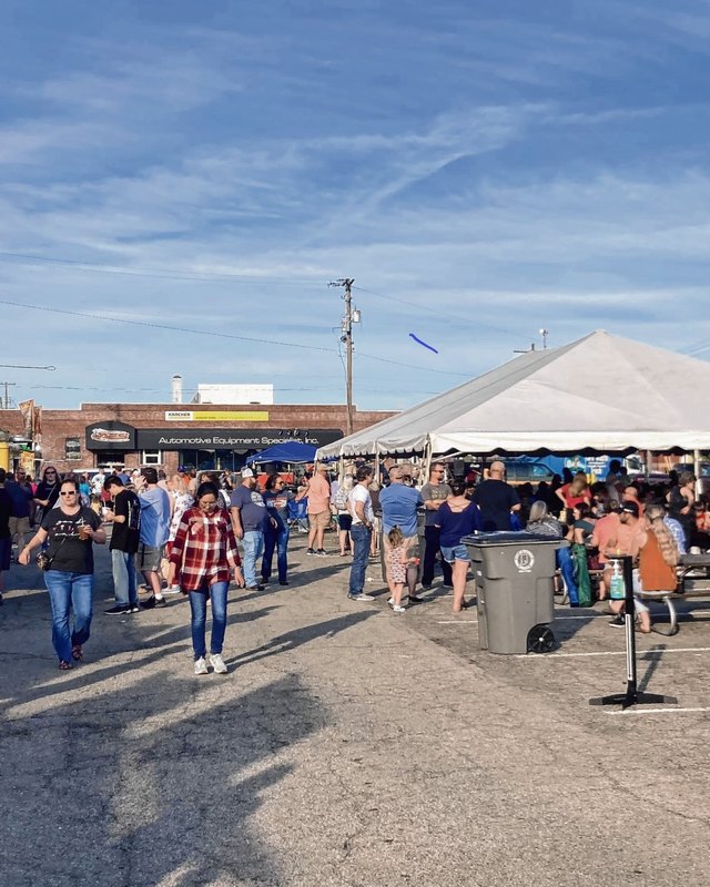 Crowds walking past festival tents and food booths on a sunny street at Frühlingsfest in Seymour.
