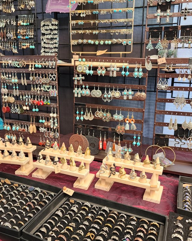 Handmade earrings displayed on wooden racks at a crowded market vendor booth