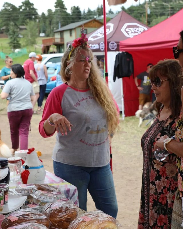 Shoppers and vendors at a baked-goods booth under red tents at Elevation Celebration in Conifer.