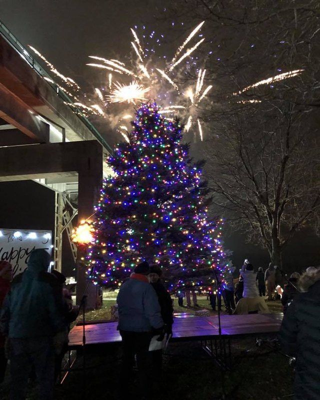 Large lit Christmas tree with fireworks and a crowd gathered for the tree lighting