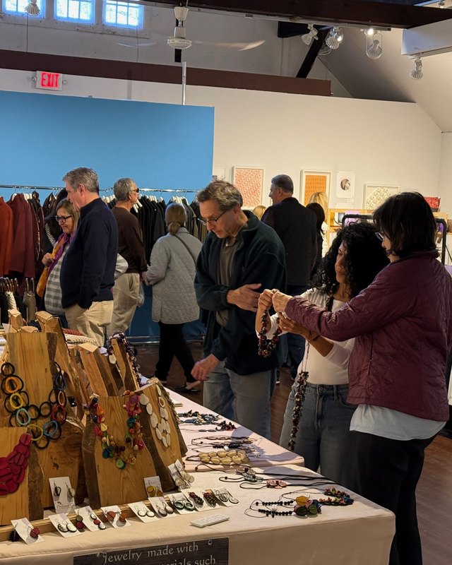 Shoppers browsing jewelry and ceramic plate booths inside the Silvermine Arts Center gallery during the Artisans Market.