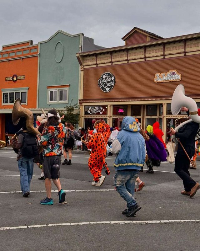Costumed performers dancing on a downtown Arcata street lined with storefronts
