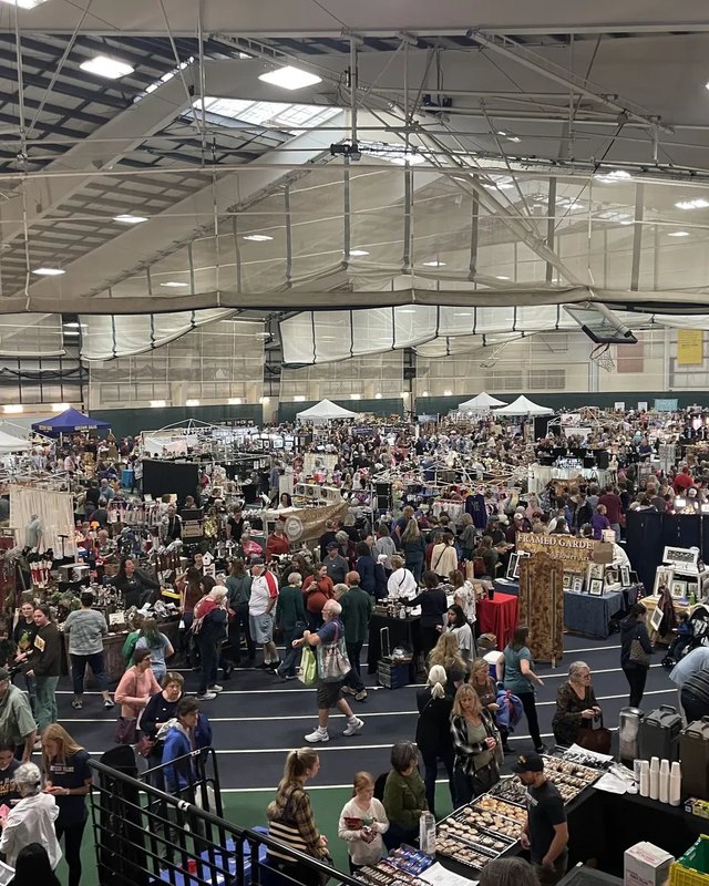 Shoppers browsing craft booths inside a large indoor gymnasium at the USM craft show.