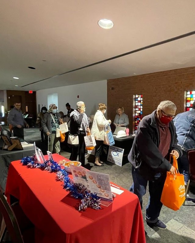 Shoppers browsing exhibit tables and banners at an indoor resource fair