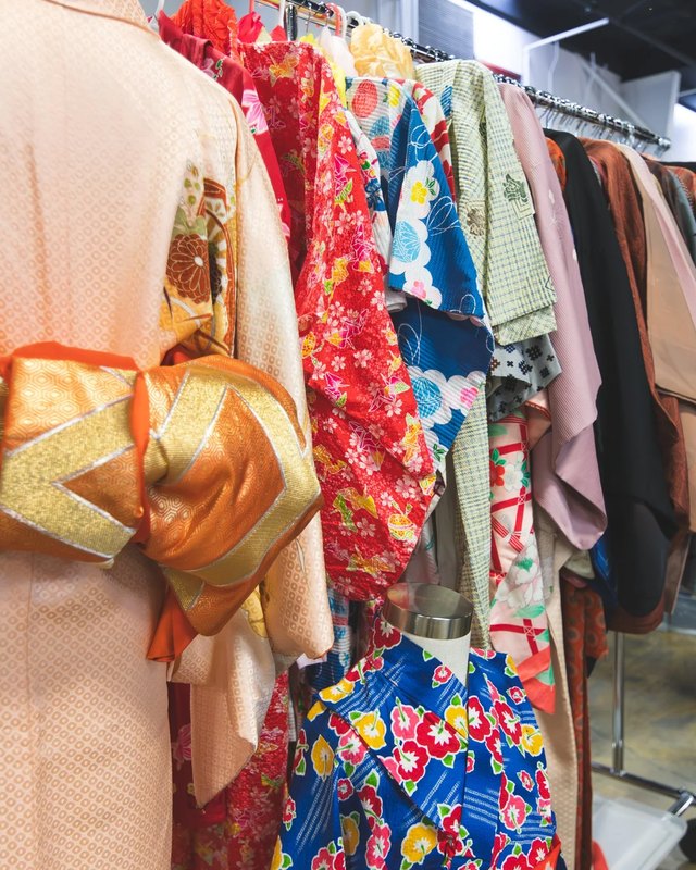 Kimono and colorful garments hanging on racks at the OC Japan Fair vendor area.