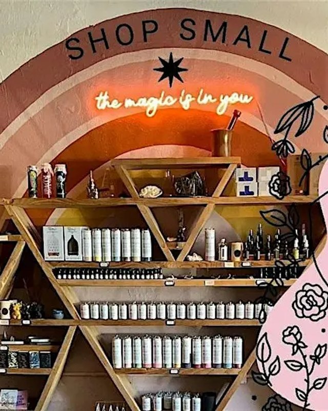 Seagrape Apothecary shop interior with a neon sign, shelves of products and a 'Shop Small' arch.