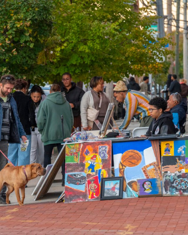 Shoppers gather around a colorful art display table on a downtown Camden street.