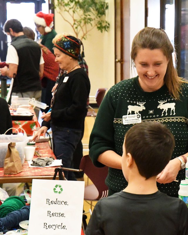Shoppers and vendors at holiday craft tables with decorated houses and wreaths at the Holiday Bazaar