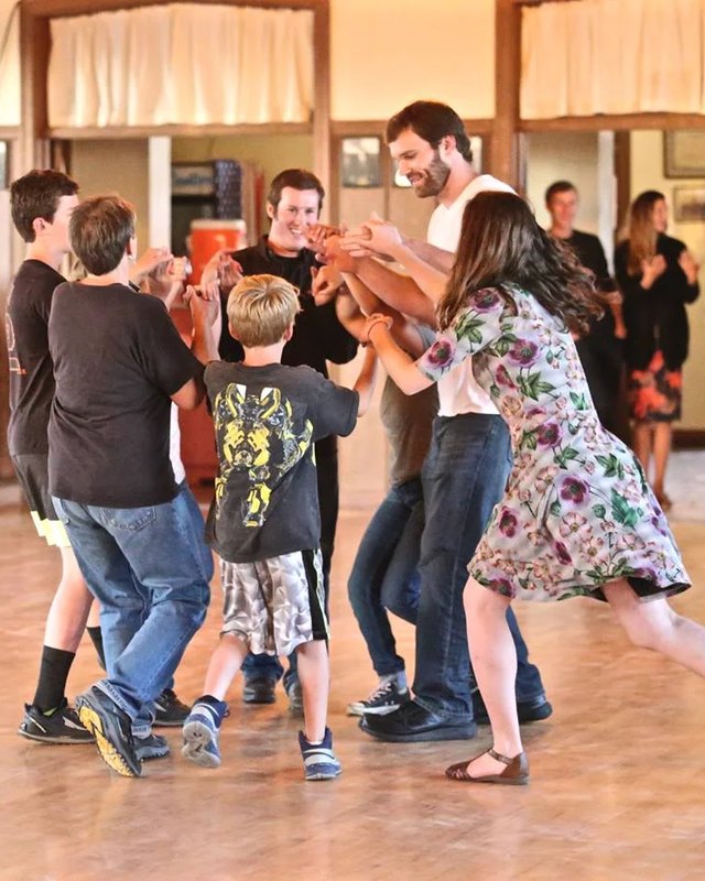 Couples and a crowd dancing on a wooden hall floor