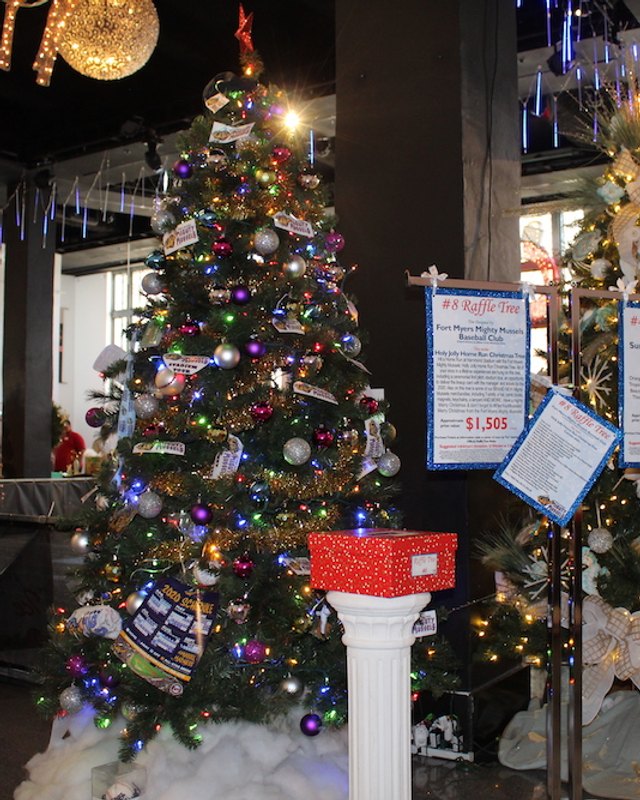 Decorated Christmas tree with raffle placards inside the Festival of Trees venue hall.