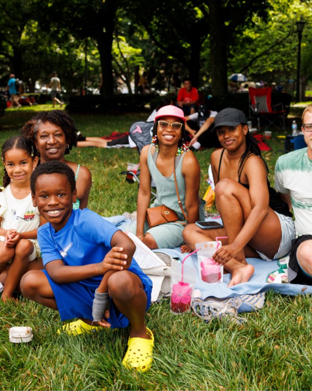 Families and kids picnicking on a grassy lawn at the Nelson-Atkins lawn party.