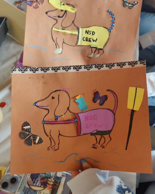 Hand-decorated dachshund drawings on orange paper at the Arts of Kenmore Oktoberfest activity table.