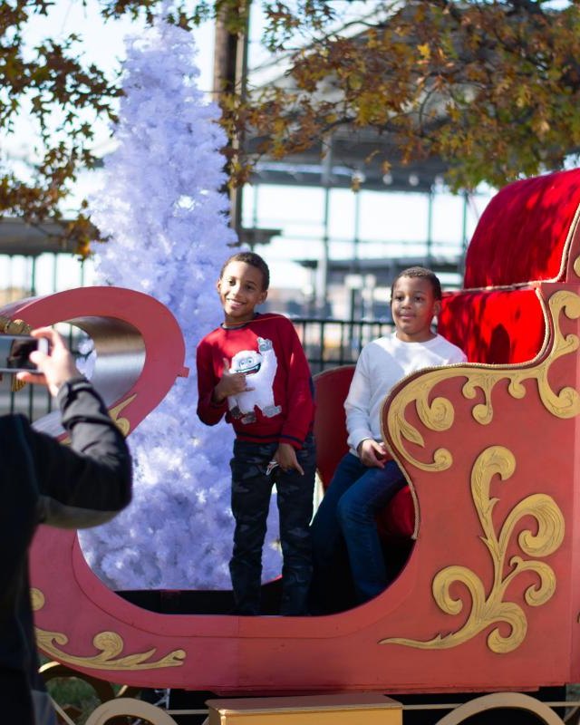 Visitors posing with a large gold and red sleigh decorated for the Addison holiday celebration
