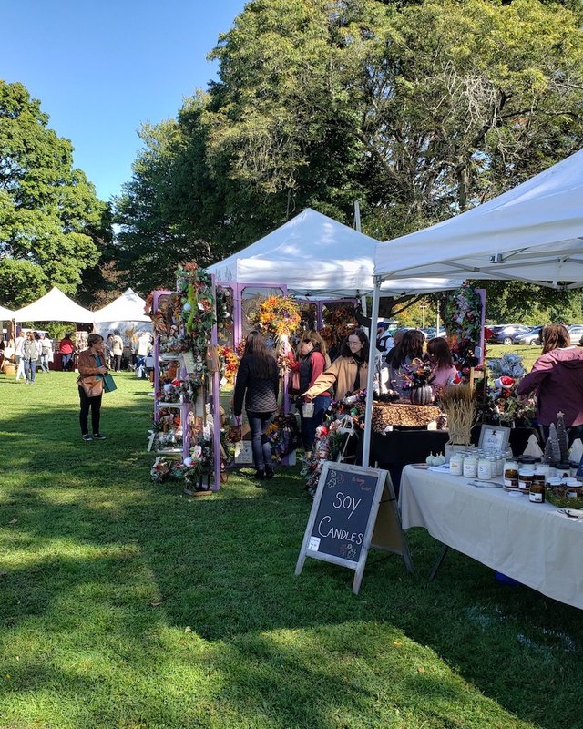 Shoppers and vendors at white tent booths on the grass during the Old Wethersfield arts and crafts fair