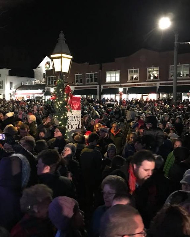 Large crowd gathered at night under string lights on a Ridgefield street during the holiday stroll.