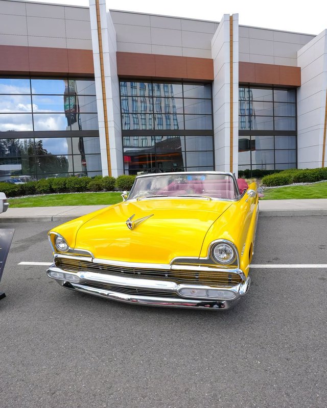 Yellow vintage convertible parked in front of the Muckleshoot Casino Resort building, with a small 'Lucille' display placard on the pavement.
