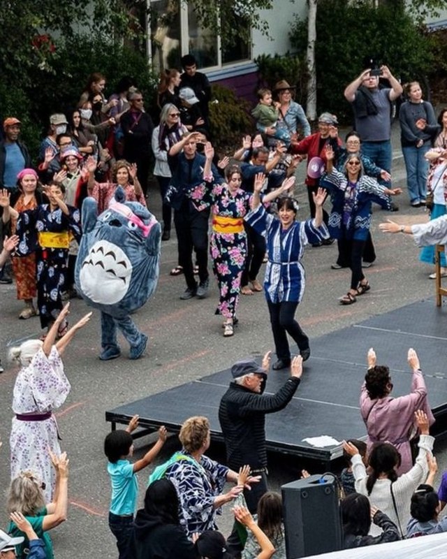A crowd in blue-and-white robes dancing around a drum stage in an outdoor plaza